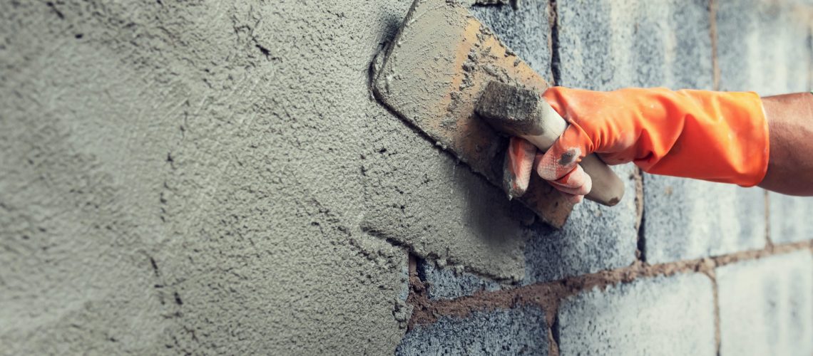 close up hand worker plastering cement on wall for building house